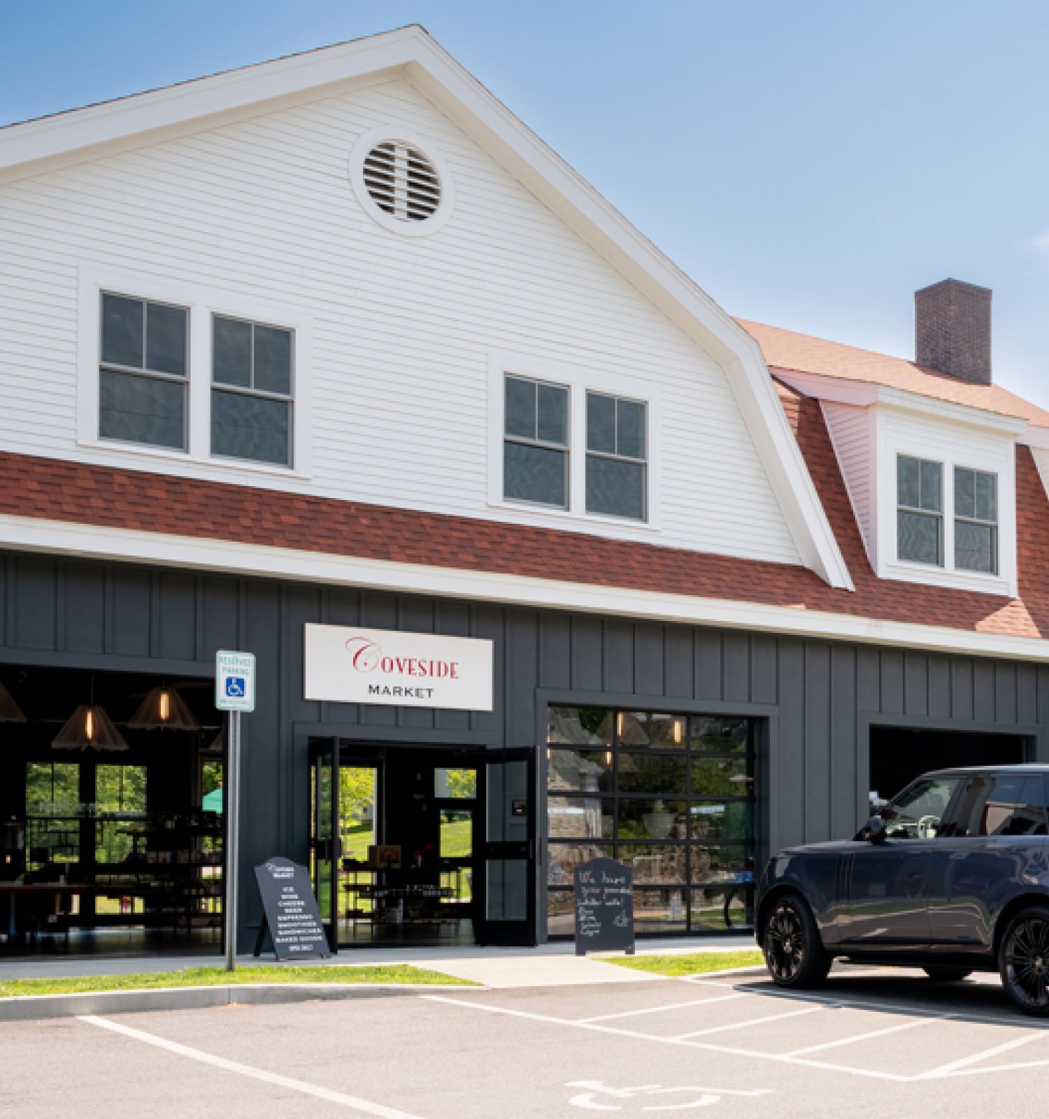A building with "Cuisine" signage, large windows, a parked black SUV in front. Overcast roof and a chimney on top complete the scene.