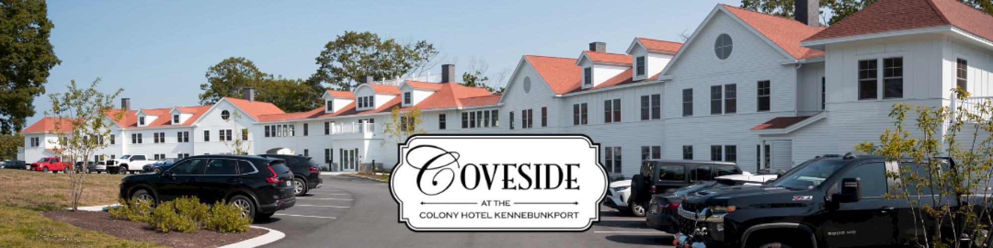 The image shows a row of white buildings with red roofs, cars parked along a driveway, and a sign that reads "COVESIDE."